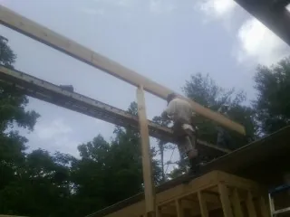 Carpenter setting a ridge beam over a new addition frame in Sanborn