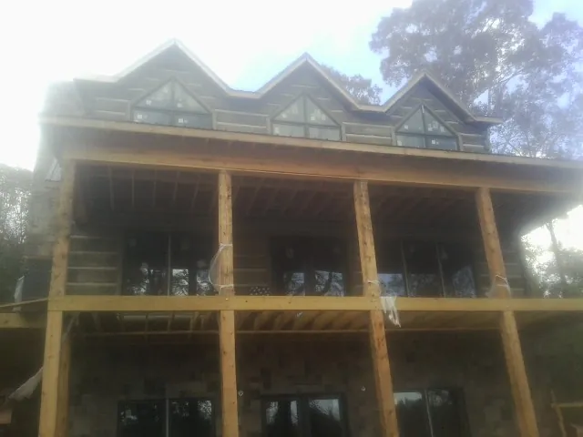 Dormers and porch framing on a large log home under construction — Roof Coating work by our crew in Sanborn