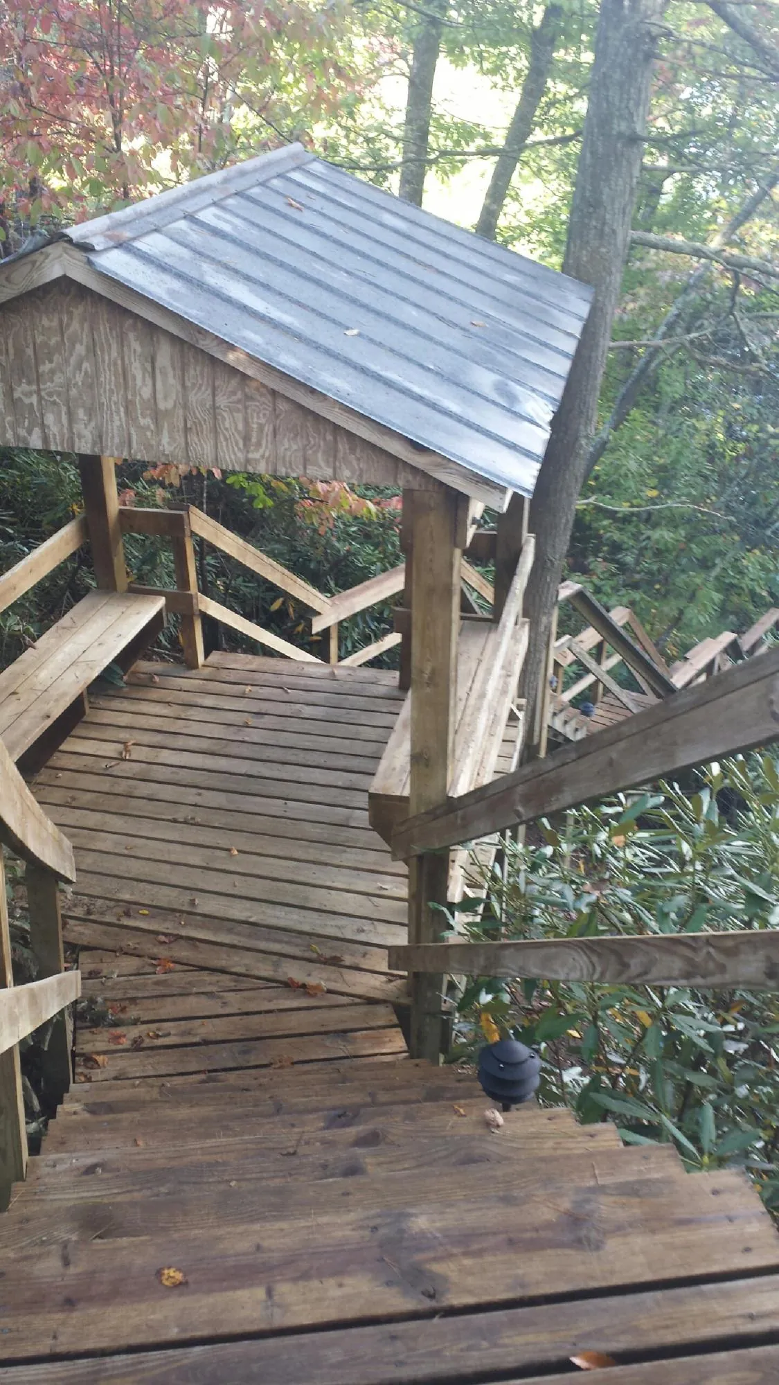Metal roofed shelter over wooden steps on a wooded walkway — Skylight Repair & Installation work by our crew in Sanborn